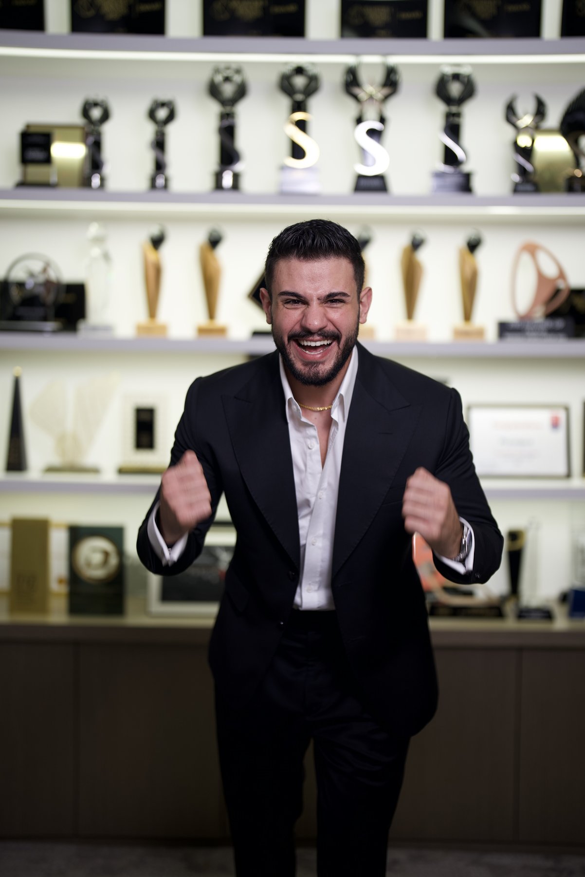Wissam Baradhi celebrating in front of his awards wall